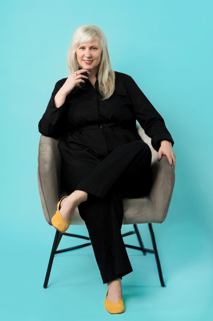 Real estate agent wearing a black jumpsuit and yellow flats during her colorful headshot session