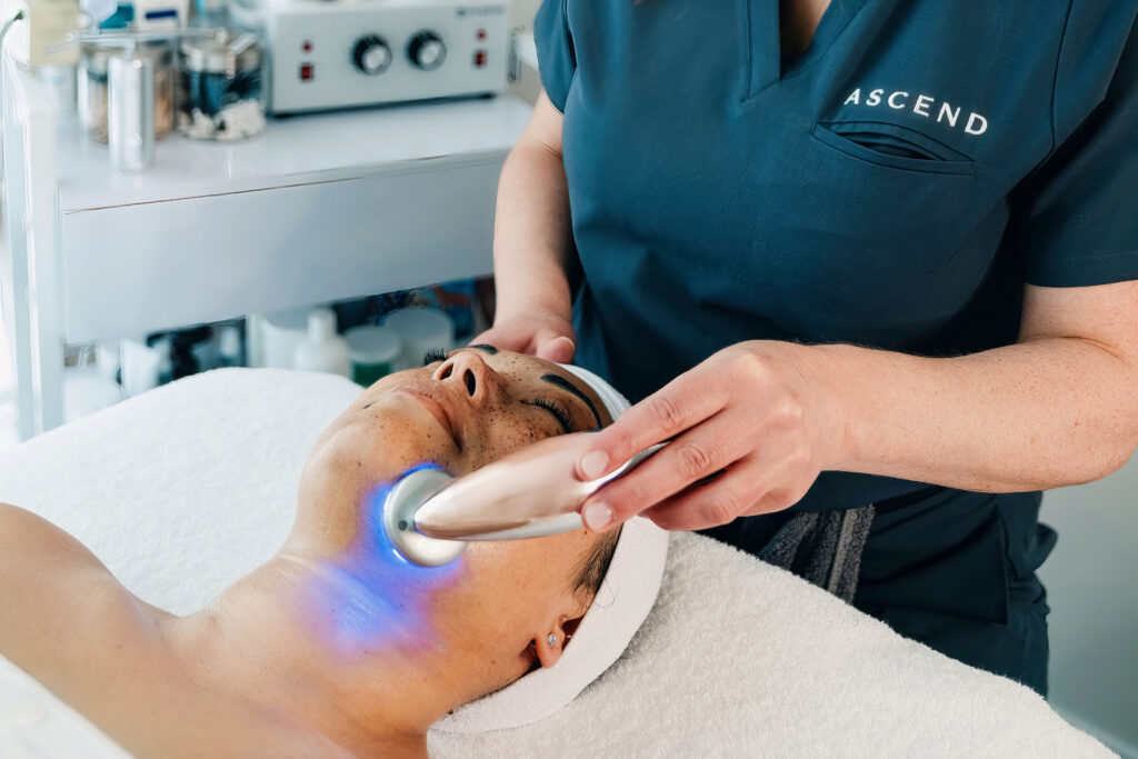 Professional brand photography session showing esthetician performing facial treatment with LED device, illustrating the difference from DIY brand photos