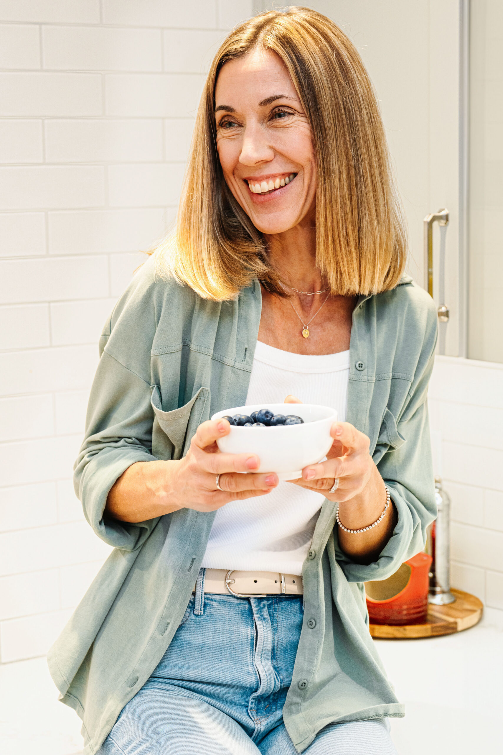 Nutritionist holding a bowl of blueberries nd smiling while looking to the side