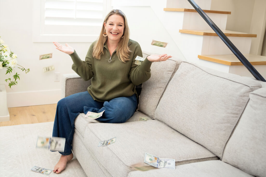 Smiling financial advisor during a brand photography session siting on a couch with money falling down on her