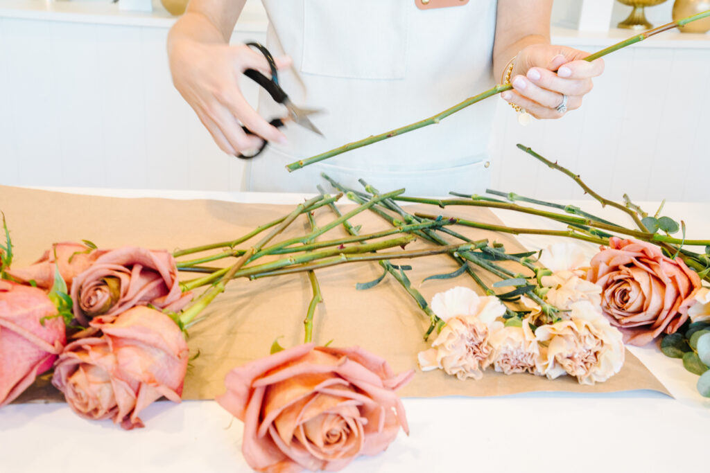 Photo of a florist's hands trimming the ends of roses.