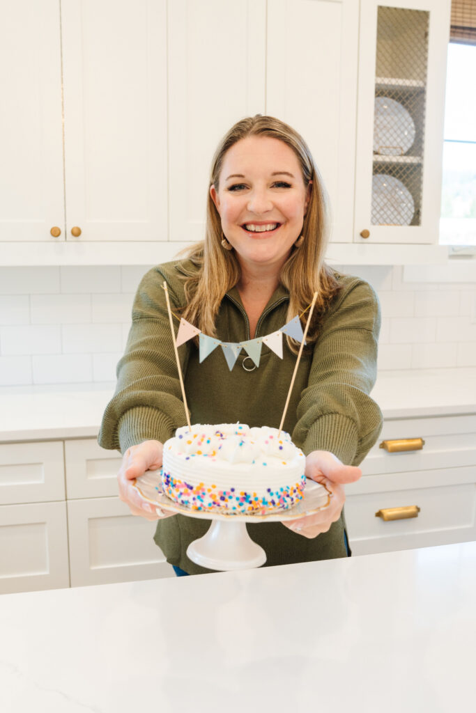 Financial catch feeling comfortable in front of the camera while holding a cake in front of her.